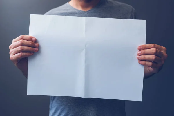 Hombre casual sosteniendo papel A3 en blanco extendido como espacio de copia —  Fotos de Stock