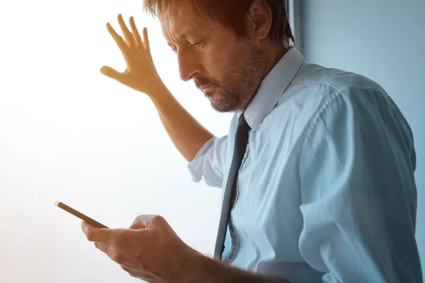 Uomo d'affari in piedi accanto alla finestra dell'ufficio e utilizzando smartphone — Foto Stock