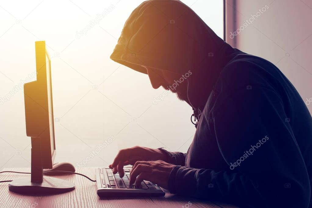 Hooded computer hacker hacking network