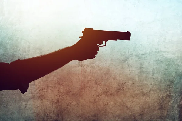 Рука с пистолетом на фоне гранжа — стоковое фото