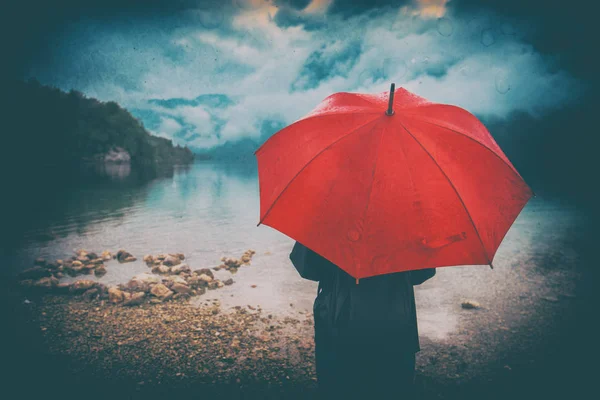 Mujer con paraguas rojo contempla la lluvia — Foto de Stock