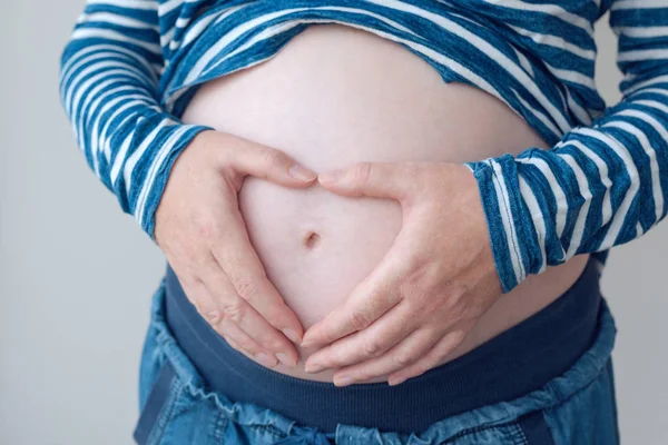 Беременная женщина трогает и потирает живот — стоковое фото