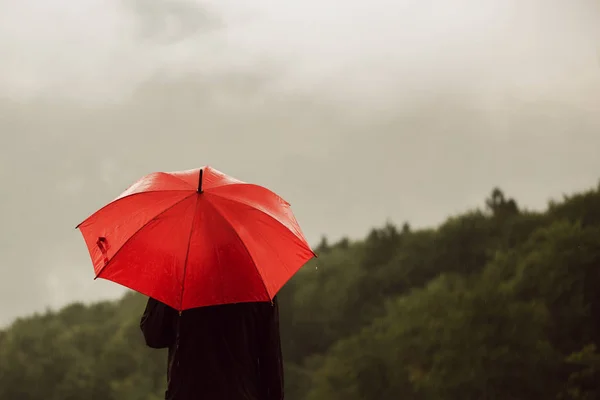 Człowiek stojący czerwony parasol w deszczu — Zdjęcie stockowe