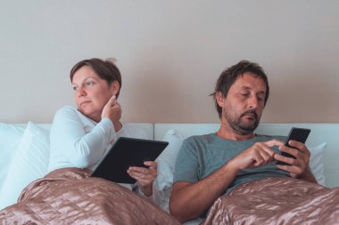 Bored couple, husband and wife in bedroom clipart