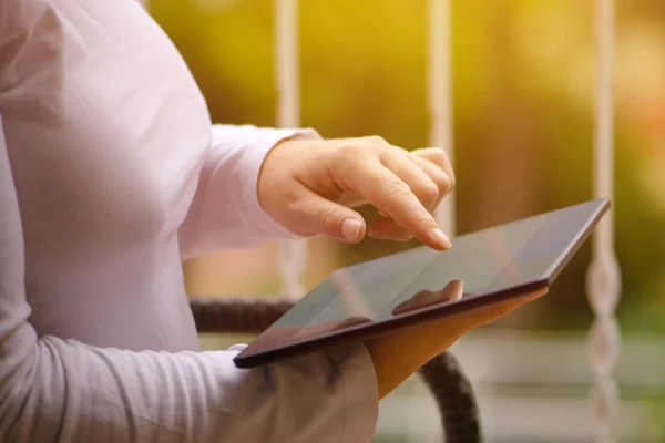 Женщина сидит на балконе и использует цифровой планшетный компьютер — стоковое фото