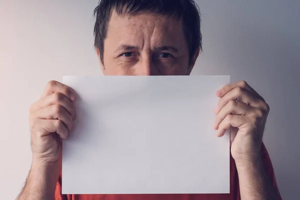 Homme caché derrière du papier blanc vierge — Photo