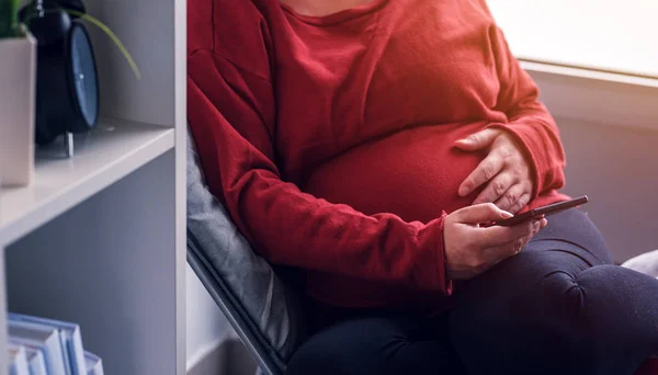 Ontspannen zwangere vrouw met behulp van slimme telefoon — Stockfoto