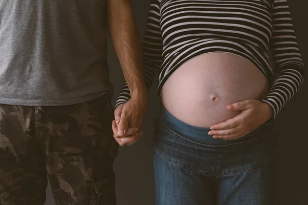 Soldat och hans gravida hustru hålla händerna — Stockfoto