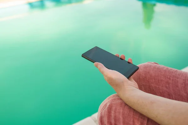 Женщина с мобильным телефоном у бассейна — стоковое фото