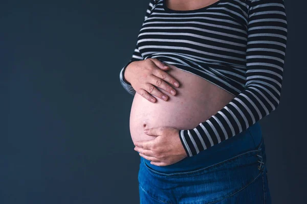 Mild kärleksfull gravid kvinna med händerna på hennes mage — Stockfoto