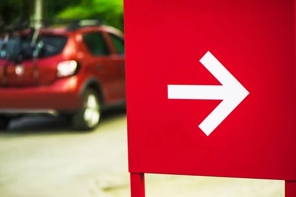 Señal de flecha de dirección con el coche en segundo plano — Foto de Stock