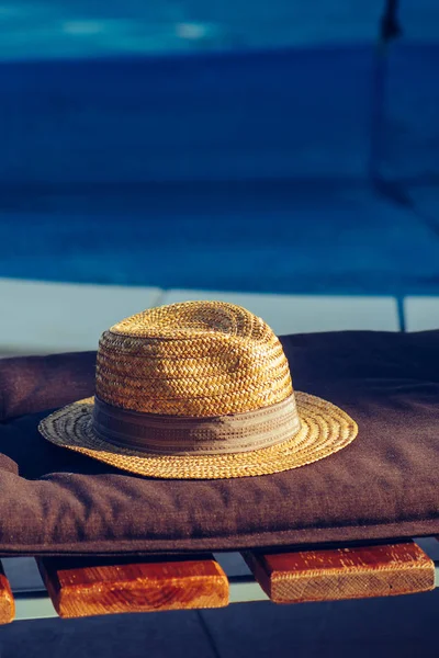 Słomkowy kapelusz na leżaku przy basenie — Zdjęcie stockowe