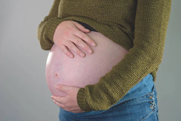 임신 한 여성의 배를 두 손으로 막고 있는 모습 — 스톡 사진