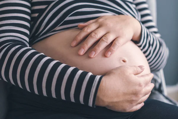 Mild kärleksfull gravid kvinna med händerna på hennes mage — Stockfoto