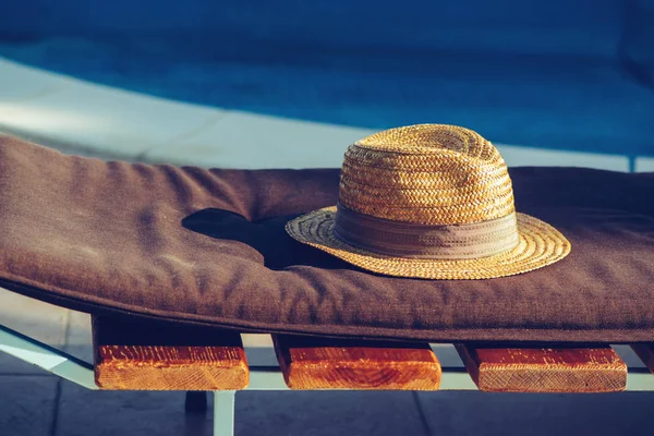 Cappello di paglia sulla sedia a sdraio a bordo piscina — Foto Stock