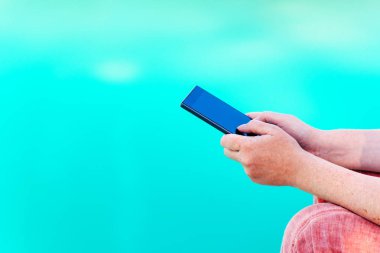 Havuz kenarında cep telefonunda kadın manifatura