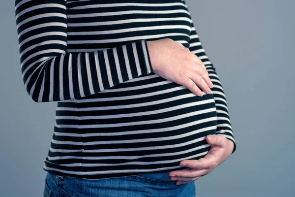 Zbliżenie kobiety w ciąży z rękami nad brzuchem — Zdjęcie stockowe