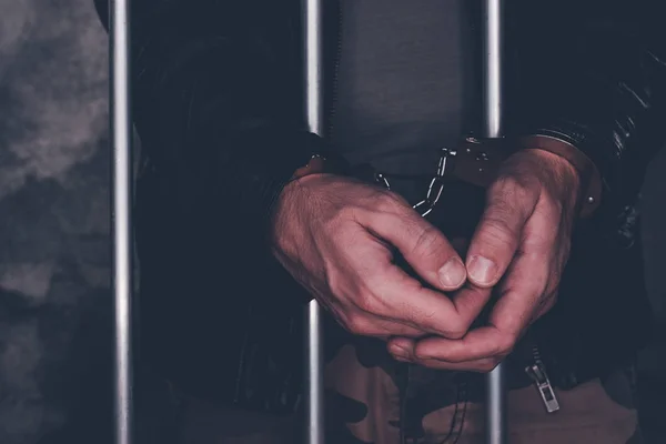 Handcuffed man behind prison bars — Stock Photo, Image