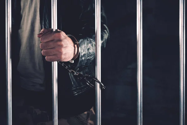 Handcuffed man behind prison bars — Stock Photo, Image