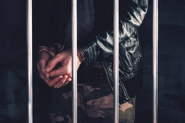 Geboeid man achter de tralies van de gevangenis — Stockfoto
