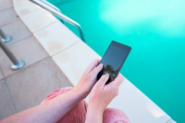 Использование мобильного телефона у бассейна — стоковое фото