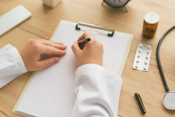 Female doctor writing notes on clipboard paper during medical ex — Stock Photo, Image