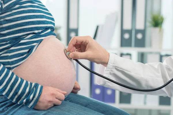 Doctor examining pregnant woman with stethoscope — Stock Photo, Image
