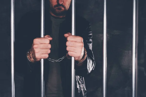 Handcuffed man behind prison bars — Stock Photo, Image