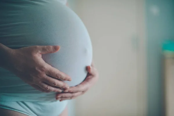 妊娠中の女性が自宅の寝室で腹を抱きしめる — ストック写真