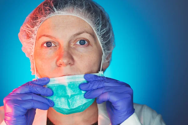 Kadın cerrah işleminden önce koruyucu cerrahi maske koyar — Stok fotoğraf