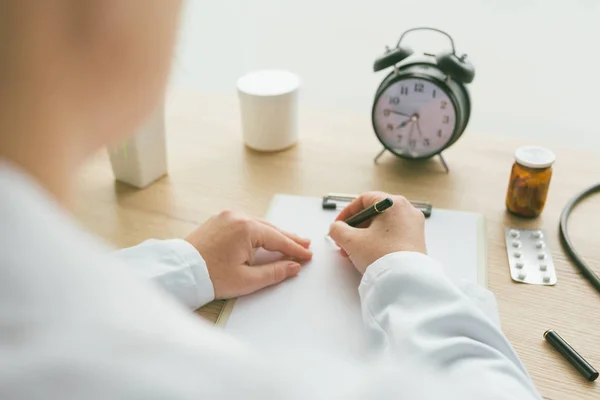 Vrouwelijke arts schrijven van notities op Klembord papier tijdens medische ex — Stockfoto