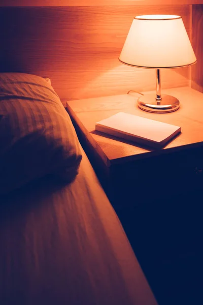 Buch und Vintage-Lampe auf Nachttisch im Hotelzimmer — Stockfoto