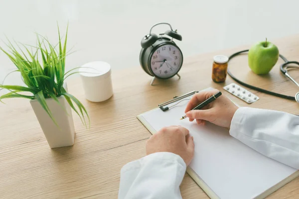 Doctora escribiendo notas en papel portapapeles durante el ex médico —  Fotos de Stock