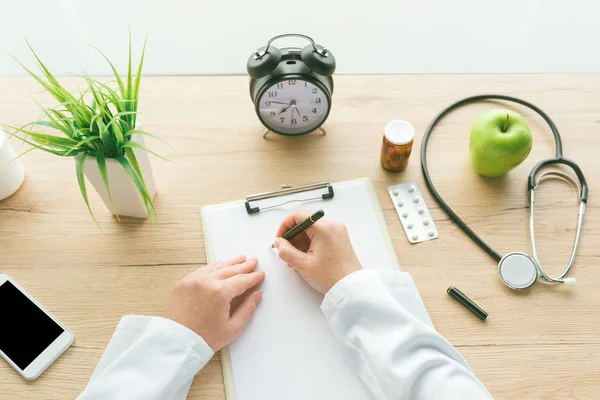 Doctora escribiendo notas en papel portapapeles durante el ex médico —  Fotos de Stock