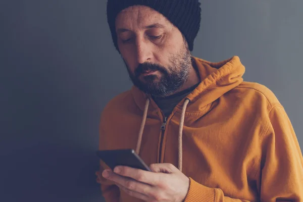 Hombre adulto casual con gorra mirando el teléfono móvil —  Fotos de Stock