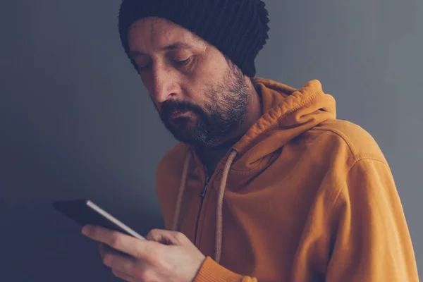 Hombre adulto casual con gorra mirando el teléfono móvil —  Fotos de Stock