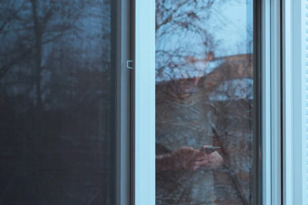 Solo triste hombre usando el teléfono móvil por la ventana — Foto de Stock