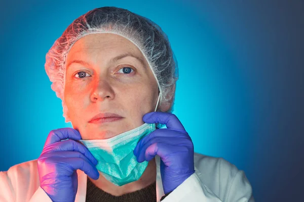 Female surgeon takes off protective surgical mask after operatio