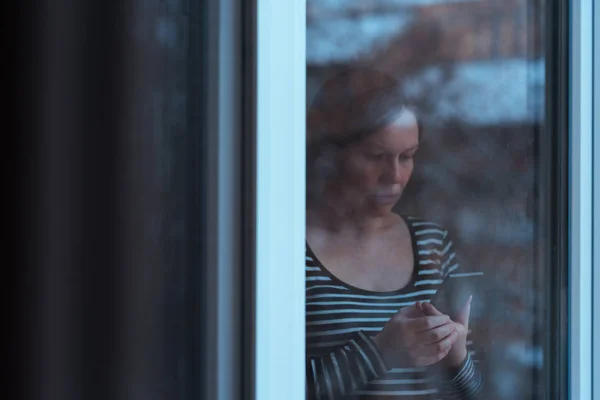 Sozinho triste homem usando telefone celular pela janela — Fotografia de Stock