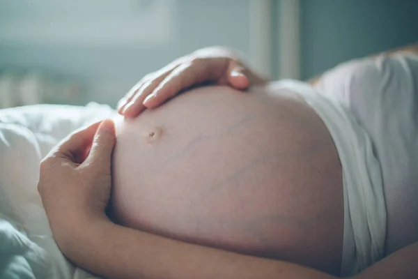 Schwangere kuschelt Bauch im Schlafzimmer zu Hause — Stockfoto