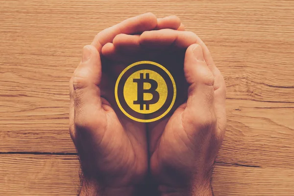 Bitcoin cryptocurrency symbol in cupped male hands — Stock Photo, Image