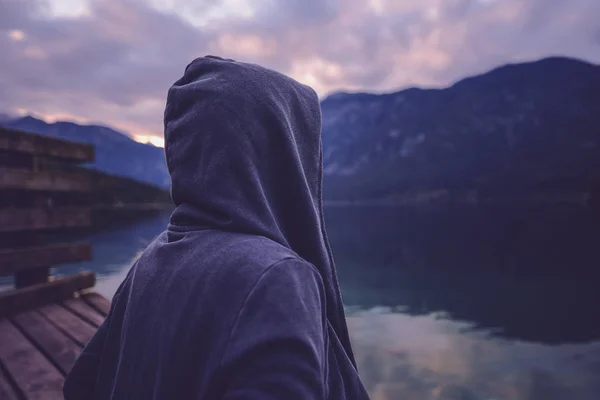 Persona solitaria incappucciata in piedi vicino al lago — Foto Stock