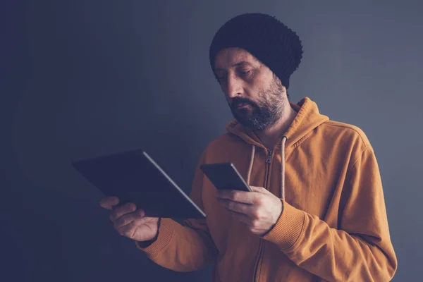 Uomo guardando il suo smartphone e tablet schermo — Foto Stock