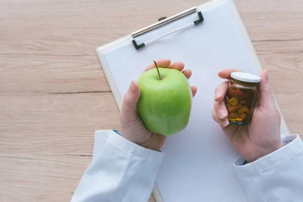 Médico aconsejando manzana en lugar de pastillas y antibióticos —  Fotos de Stock
