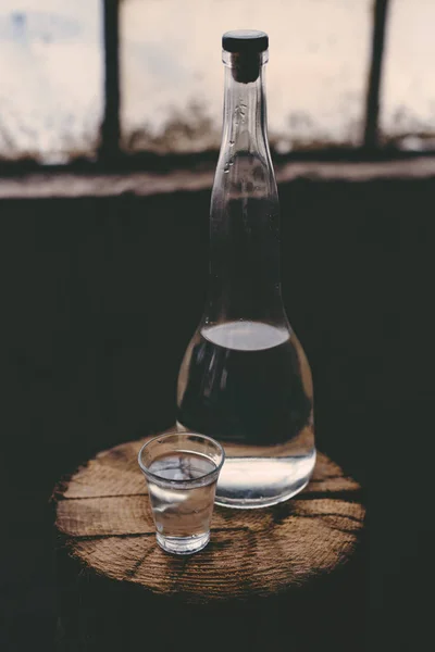 Stark alkohol dryck i flaska med snapsglas — Stockfoto