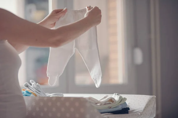 Madre clasificando ropa de bebé recién nacido en casa — Foto de Stock