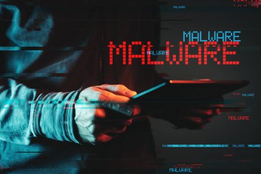 Kötü amaçlı yazılım kavramı ile tablet bilgisayarı kullanan kişi
