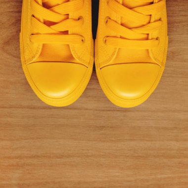 Ahşap arka plan üzerinde şık sarı spor ayakkabı