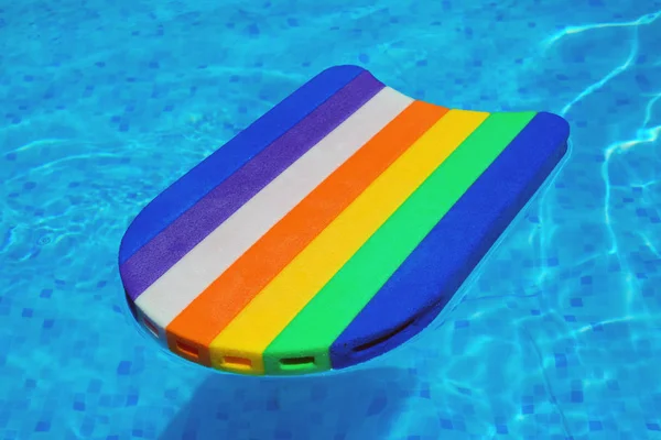 Rainbow pattern styrofoam swimming board baseboard floating in p — Stock Photo, Image
