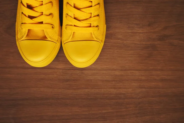 Стильні жовті кросівки на дерев'яному фоні — стокове фото